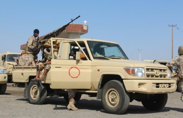 Yemeni forces stand on the back of an armed vehicle at the entrance to Abyan province as t