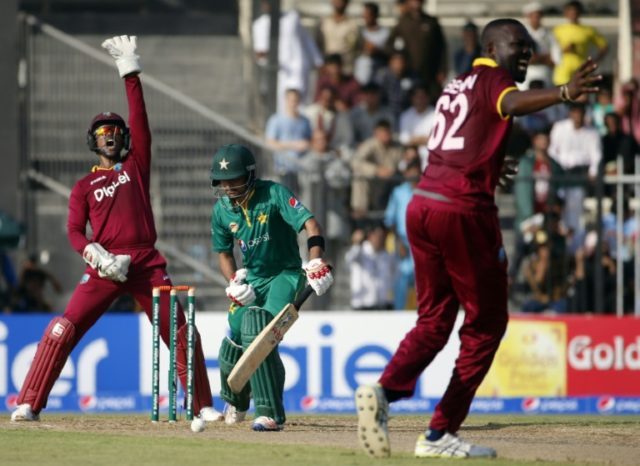 Pakistan's batsman Babar Azam (C) reacts after being bowled out by West Indies' during the