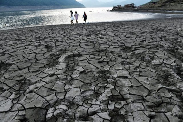 People walk along a dried and cracked river beach of the Yangtze River in China