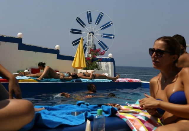 Sunseekers relax by the pool at a beach resort in the coastal Lebanese town of Anfeh, nort