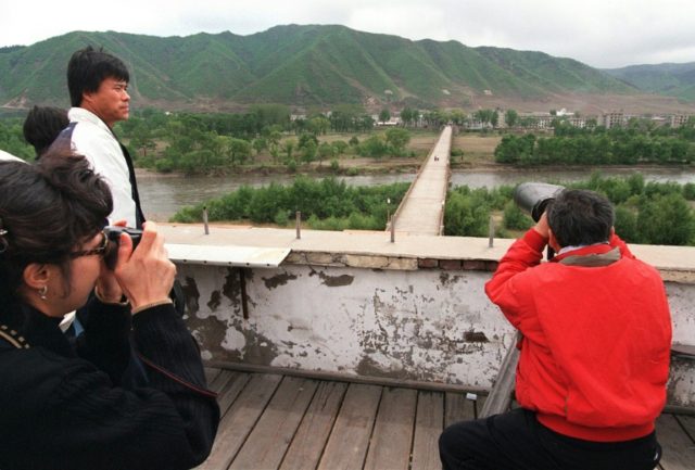 South Korean tourists look across the Tumen River into North Korea from an observation poi
