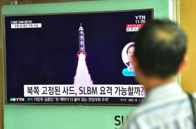 A man watches a television screen reporting news of North Korea's latest submarine-launche