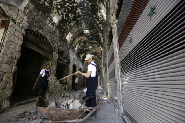 Members of the United Nations Development Programme work in a damaged alley of the ancient