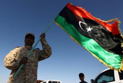 A member of forces opposed to Libya's unity government waves a Libyan flag at the Zueitin