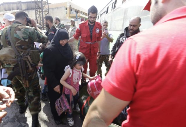Members of the Syrian Red Crescent help the families of opposition fighters carry their be