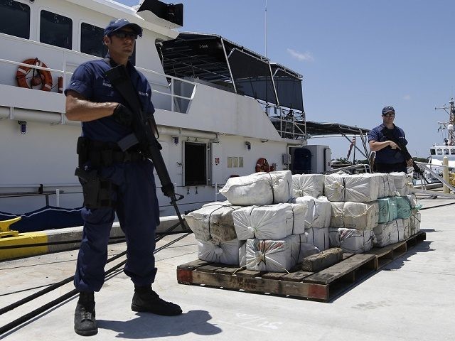 Coast Guard crew members from the cutter Bernard C. Webber stand guard next to bales of cocaine, Friday, April 26, 2013 at the U.S. Coast Guard base in Miami Beach, Fla. The 2,200 pounds of cocaine, worth an estimated $27 million, was seized after stopping a fishing boat in the …