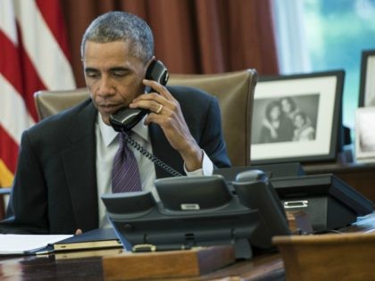 President Barack Obama speaks on the phone in the Oval Office of the White House October 8, 2014 in Washington, DC. Obama participated in a conference call to discuss the US response to the current Ebola outbreak. AFP PHOTO/Brendan SMIALOWSKI (Photo credit should read
