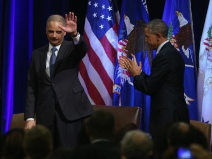 Eric Holder waves while applauded by colleagues and US President Barack Obama (R) during h