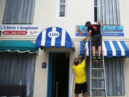 Danny Askins and Brenden Kavana (R) put up hurricane shutters as they prepare the Sandwich