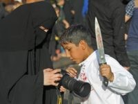 An Iraqi Shiite boy looks at his picture during the reenactment of the Battle of Karbala, as part of a parade in preparation for the peak of the mourning period of Ashura, on October 11, 2016 in Baghdad's northern district of Kadhimiya. The religious festival of Ashura, which includes a …