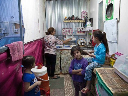 Intisar Mateh, second left, washes the dishes as her daughter, Farah Mateh, right, plays w