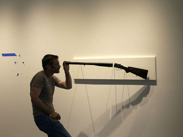 In this Friday, Sept. 26, 2014 photo, artist Adam Mysock installs his artwork, titled "Looking Down The Barrel of a Gun (The Last Judgement)," for the upcoming exhibit "Guns in the Hands of Artists," at the Jonathan Ferrara Gallery in New Orleans. (AP Photo/Gerald Herbert)