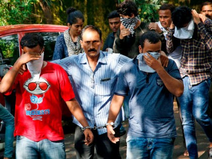 A police official, center, escorts two men outside the court in Thane, outskirts of Mumbai