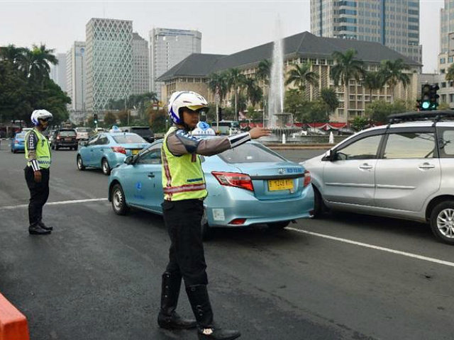 Police officers stand on a main road in Jakarta on Aug. 30, 2016, as a new traffic control