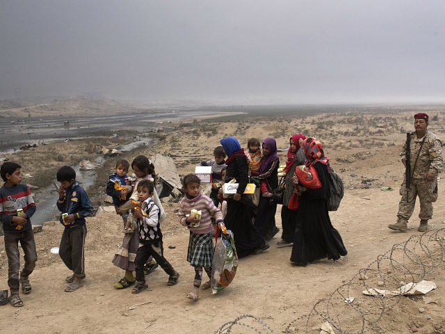 Internally displaced persons clear a checkpoint in Qayara, some 50 kilometers south of Mos