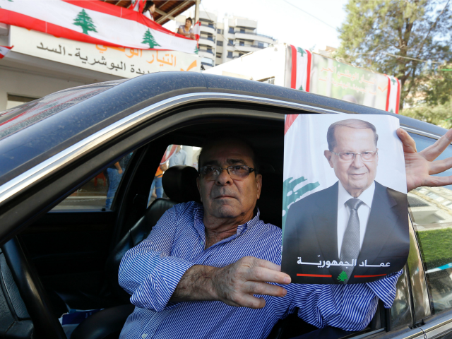 A supporter of Lebanese presidential candidate Michel Aoun holds his portrait ahead of a p