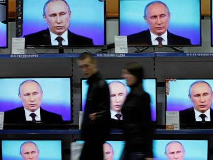 Visitors walk past TV sets during Russian President Vladimir Putin's live broadcast nation