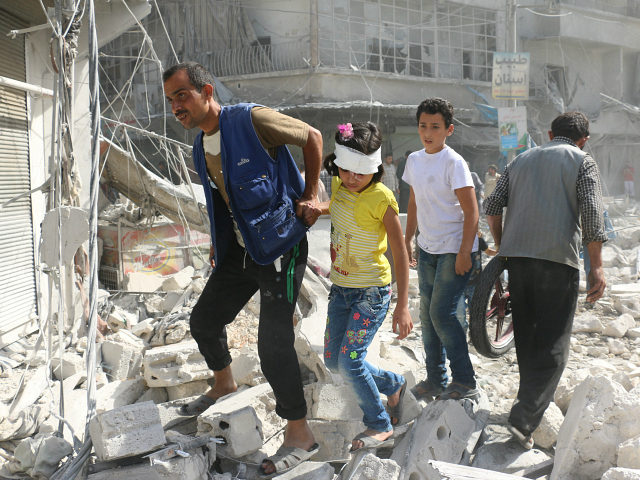 Syrians walk over rubble following air strikes on the rebel-held Fardous neighbourhood of
