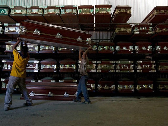 Workers carry a coffin in a caskets factory in Caracas November 29, 2012. REUTERS/Carlos Garcia Rawlins