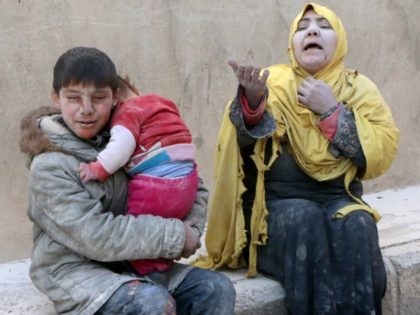 A woman, a young boy and a baby, covered with dust, sit in a state of shock following a reported air strike attack by government forces on the Hanano district of the northern Syrian city of Aleppo on February 14, 2014. Syria's warring sides began what was expected to be …