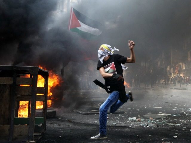 A masked Palestinian hurls rocks towards Israeli soldiers during clashes following the fun