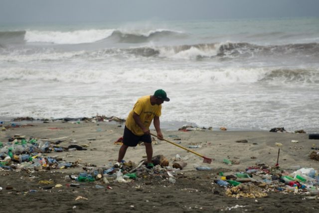 People clean the coastline of Santo Domingo, near the Port of Haina on October 3, 2016 as
