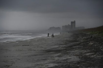 People bike on the beach ahead of hurricane Matthew in Atlantic Beach, Florida, on October