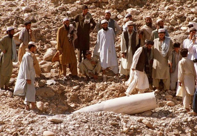 Afghans gather around an unexploded missile near the Aghna city of Jalalabad on October 14