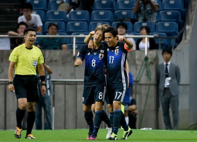 Japanese forward Genki Haraguchi (centre) celebrates with captain Makoto Hasebe after scor