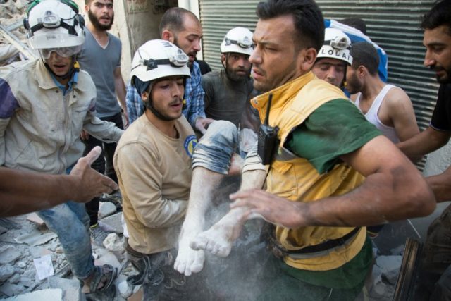 Syrian civil defence volunteers, known as the White Helmets, carry a body after digging it