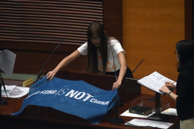 Newly elected lawmaker Yau Wai-ching, 25, lays down a banner that reads 'Hong Kong is Not