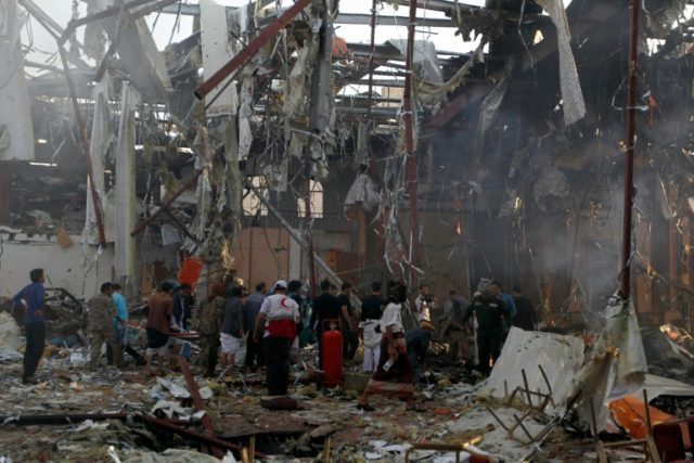 Rescue teams and bystanders gather at the site of an airstrike on a funeral hall in the ca