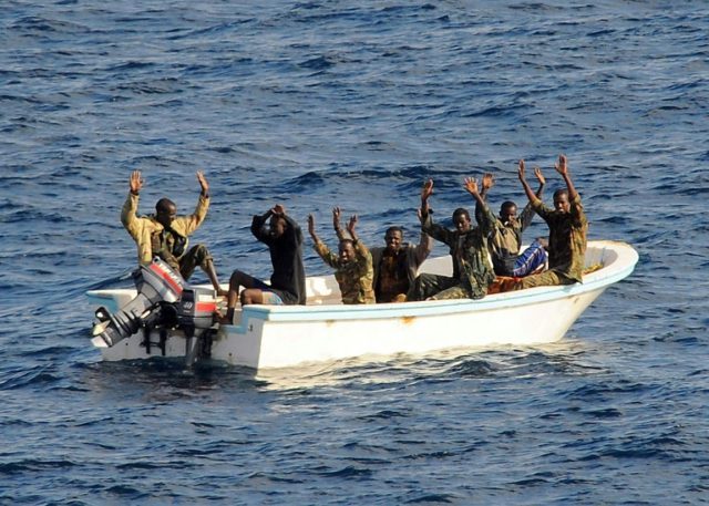 Suspected pirates keep their hands in the air as directed by a patrol from the guided-miss
