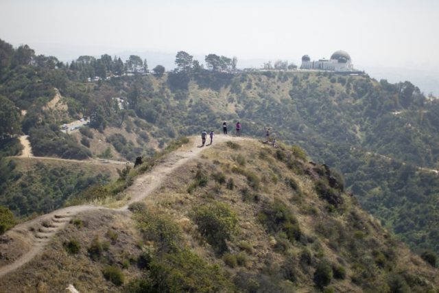 People hike along a ridge overlooking the Griffith Observatory where vegetation is drying out due to lack of rain, in Los Angeles, California