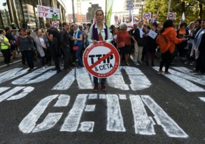 A woman holds a placard depicting a no entry sign with the TTIP and CETA logos, during a demonstration outside the European Union headquarters in Brussels, on September 20, 2016