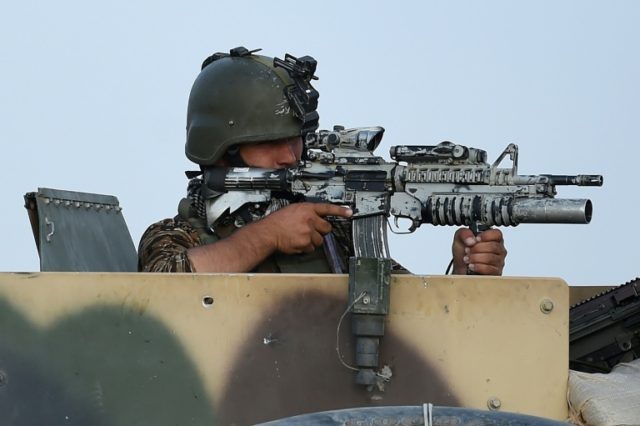 An Afghan soldier keeps watch during an ongoing battle between Taliban militants and Afgha