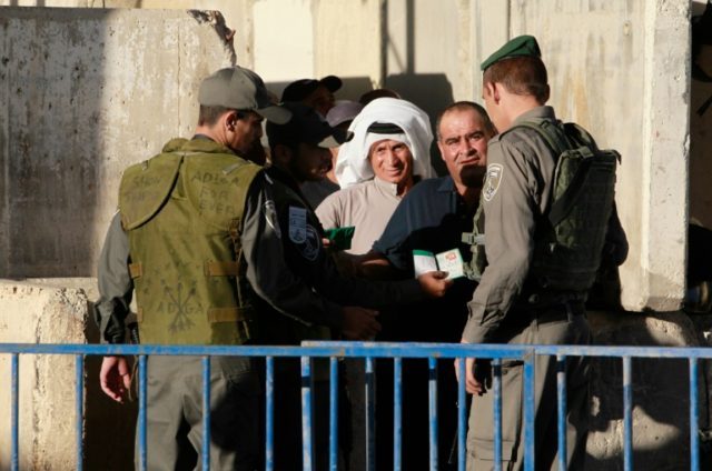 Palestinians are checked at an Israeli checkpoint between the West Bank town of Bethlehem