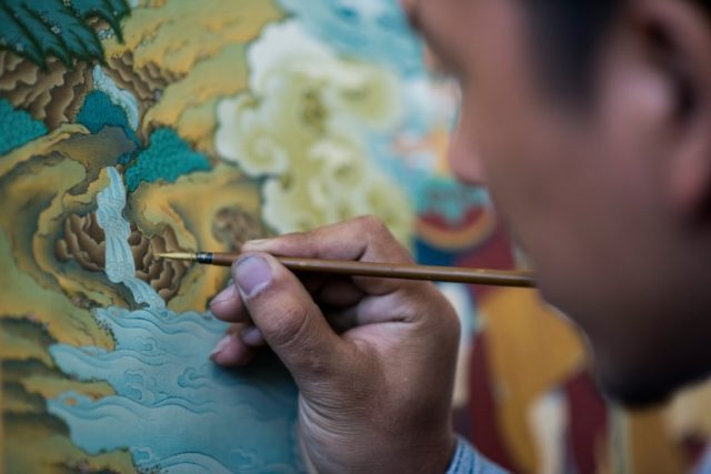 A student paints an example of the medieval Tibetan art of 'thangka', minutely detailed pa