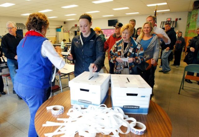 Kentucky voters place their paper ballots in the box in a GOP presidential caucus on March