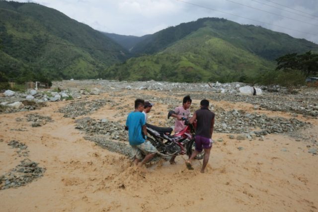 Residents carry a motorbike along a destroyed highway following heavy rains brought by Typ