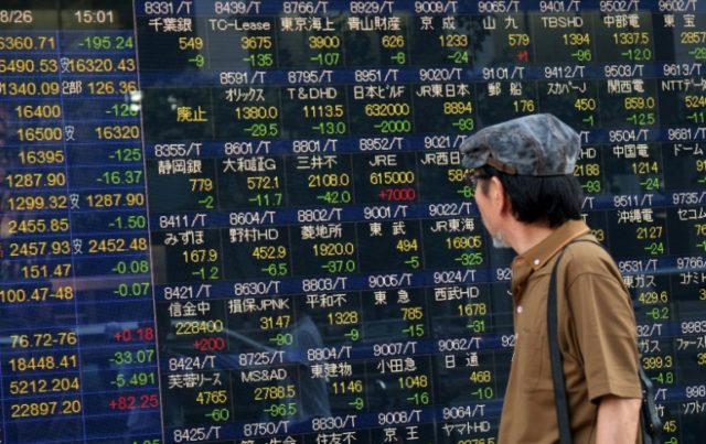 A man looks at an electric quotation board displaying the Nikkei key index of the Tokyo St
