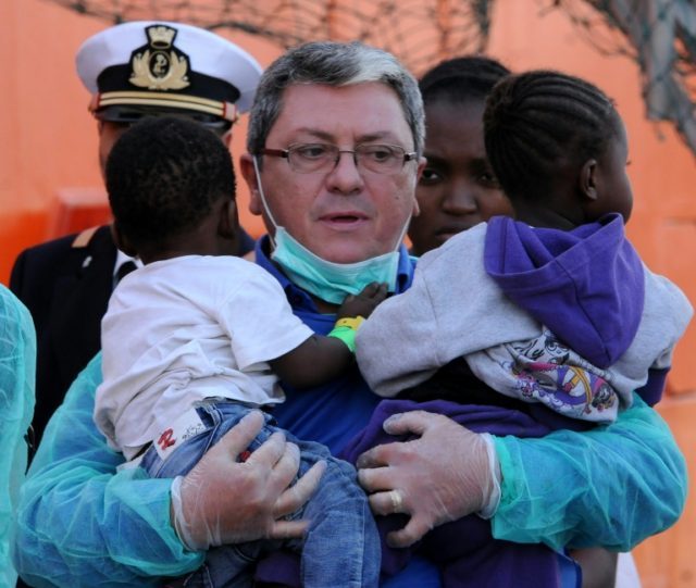 A rescuer holds two young children as migrants disembark from the Siem Pilot ship on Octob