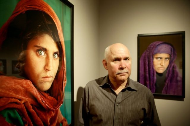 US photographer Steve McCurry poses next to his photos of the "Afghan Girl" named Sharbat