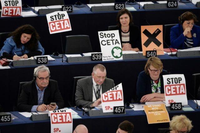 Member of European Parliament take part in a voting session, next to placards reading "Sto