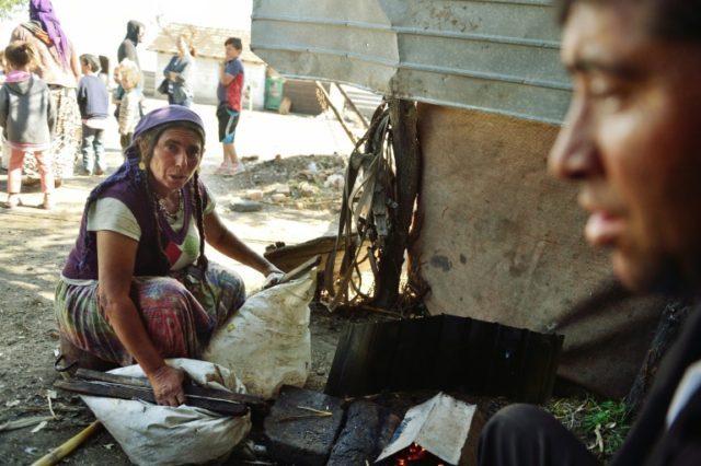A Roma woman lights a makeshift furnace to work iron in Stoenesti, southern Romania
