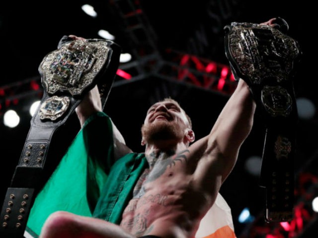 Conor McGregor holds up his title belts after he knocked out Eddie Alvarez during a lightw