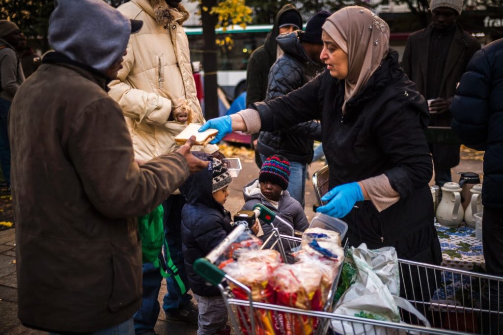 A woman gives food to migrants at a make-shift tent camp near to the Stalingrad metro station, one of several camps sprouting up around the French capital, on November 3, 2016 in Paris. Less than 300 kilometres from the recently-demolished "Jungle" migrant camp in Calais, around 2,000 migrants are living in similar conditions on the streets of Paris. uthorities are expected to soon clear the camp under a railway bridge in the northeastern Stalingrad district, with a 400-bed temporary shelter set to open in the coming days. / AFP / LIONEL BONAVENTURE (Photo credit should read LIONEL BONAVENTURE/AFP/Getty Images)