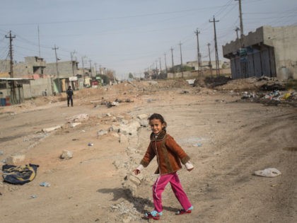 MOSUL, IRAQ - NOVEMBER 15: A young girl walks across a street just behind the frontline in