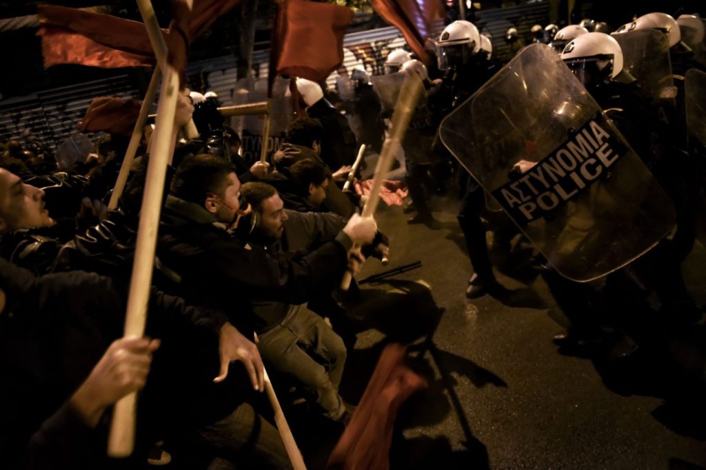 Demonstrators holding red flags clash with Greek riot police during a protest against the visit of the US president in Athens on November 15, 2016. US President Barack Obama is in Greece on a two-day official visit. / AFP / ARIS MESSINIS (Photo credit should read ARIS MESSINIS/AFP/Getty Images)