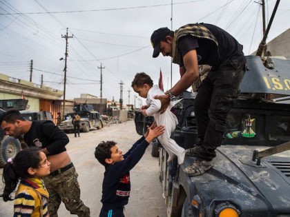TOPSHOT - Children emerge from their houses to greet soldier from the Iraqi Special Forces 2nd division during a lull in the fighting with IS fighters while pushing into the Aden neighbourhood in Mosul on November 16, 2016. Iraqi forces have broken into jihadist-held Mosul and recaptured neighbourhoods inside the …